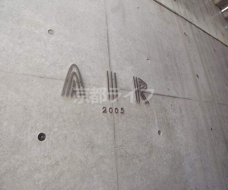 壁にメタルな素材で掲げられた「AIR」のマンション名